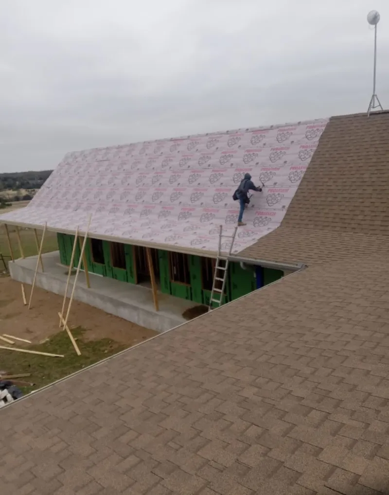 Worker preparing underlayment for a metal roof installation in Freeport